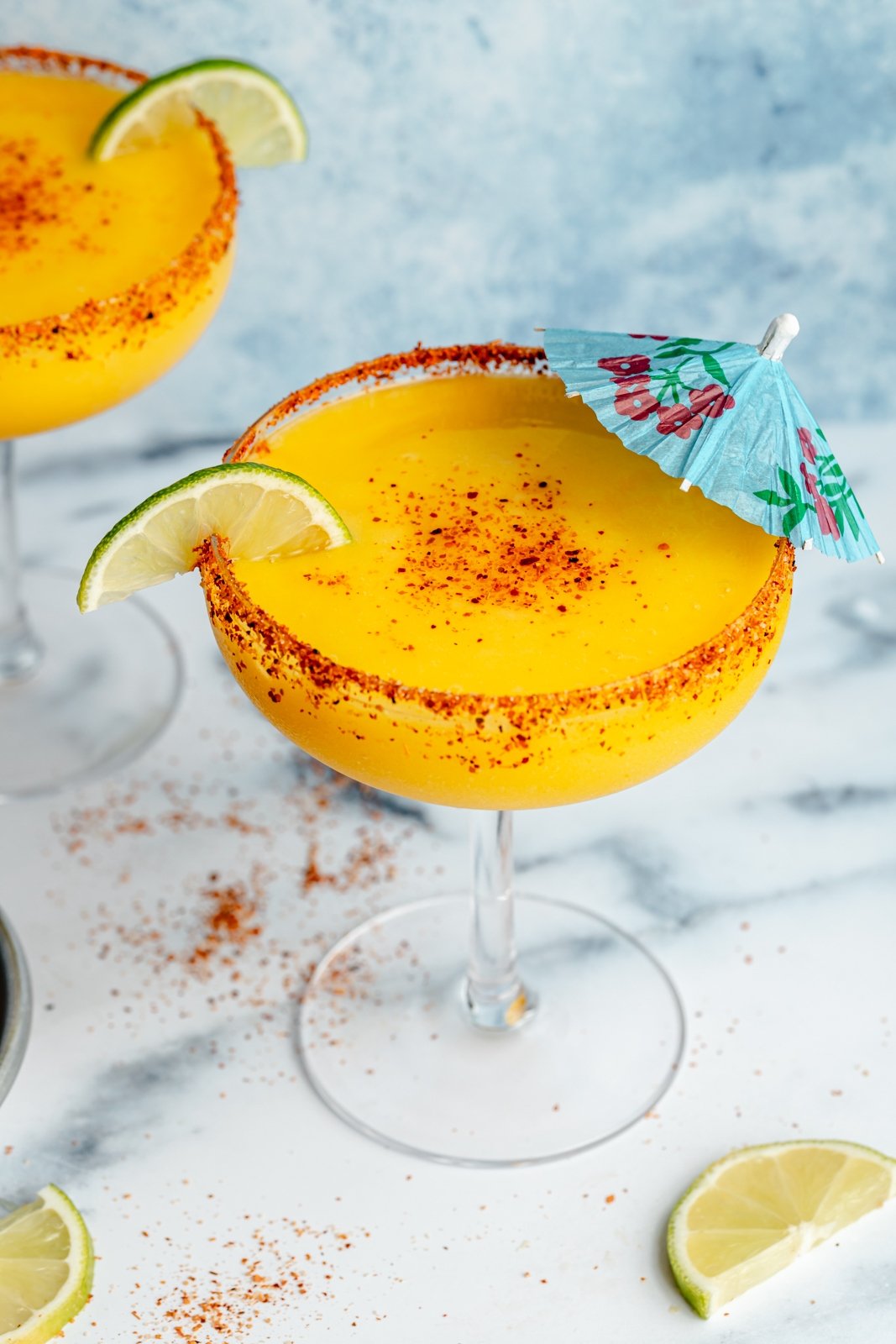 4-ingredient frozen mango margarita in a glass with a blue umbrella