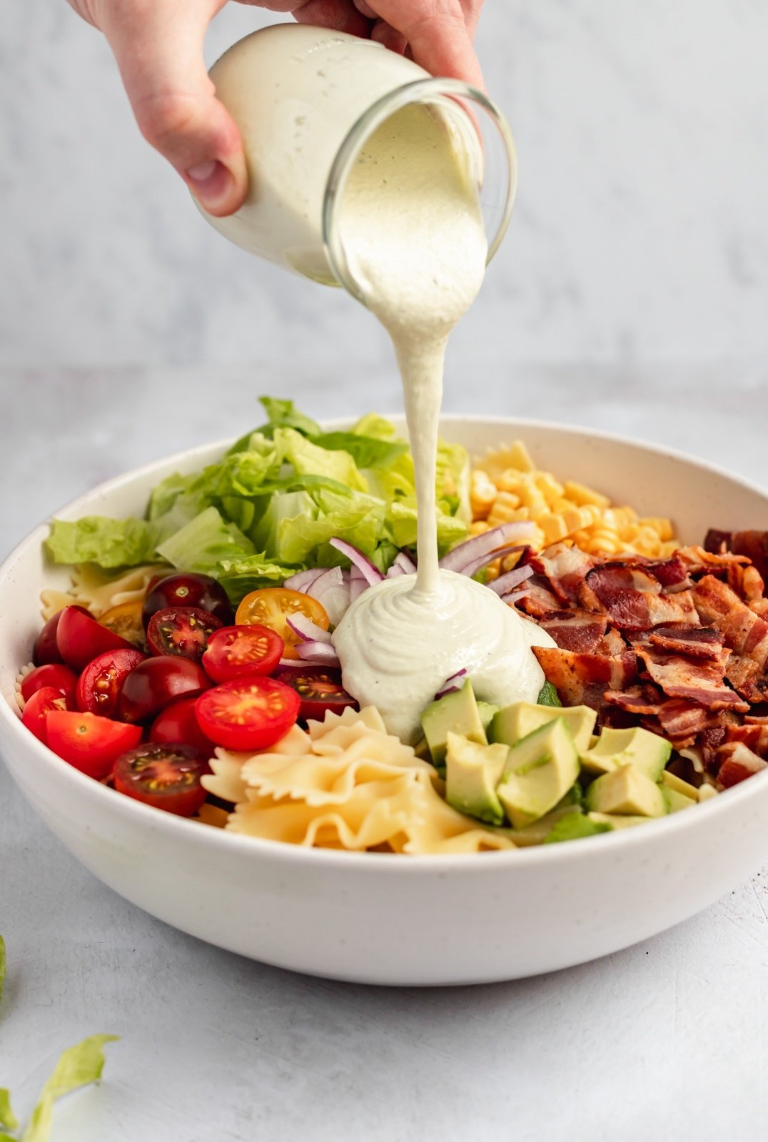 pouring vegan cashew cream sauce into a salad bowl