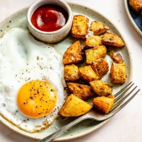 breakfast potatoes, an egg, and ketchup on a plate