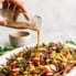 pouring sesame ginger dressing onto a salad