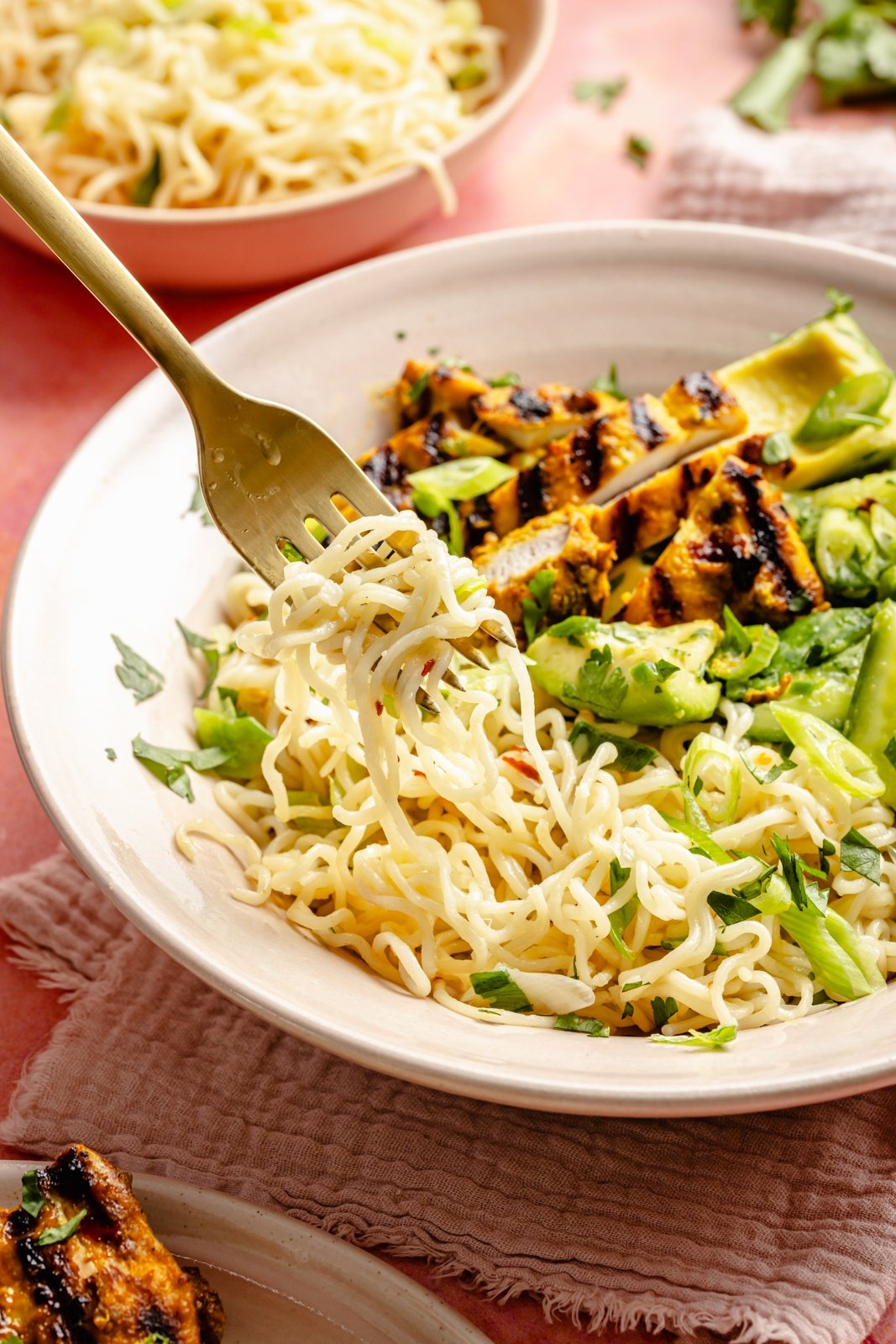 scooping ramen out of a grilled turmeric chicken bowl